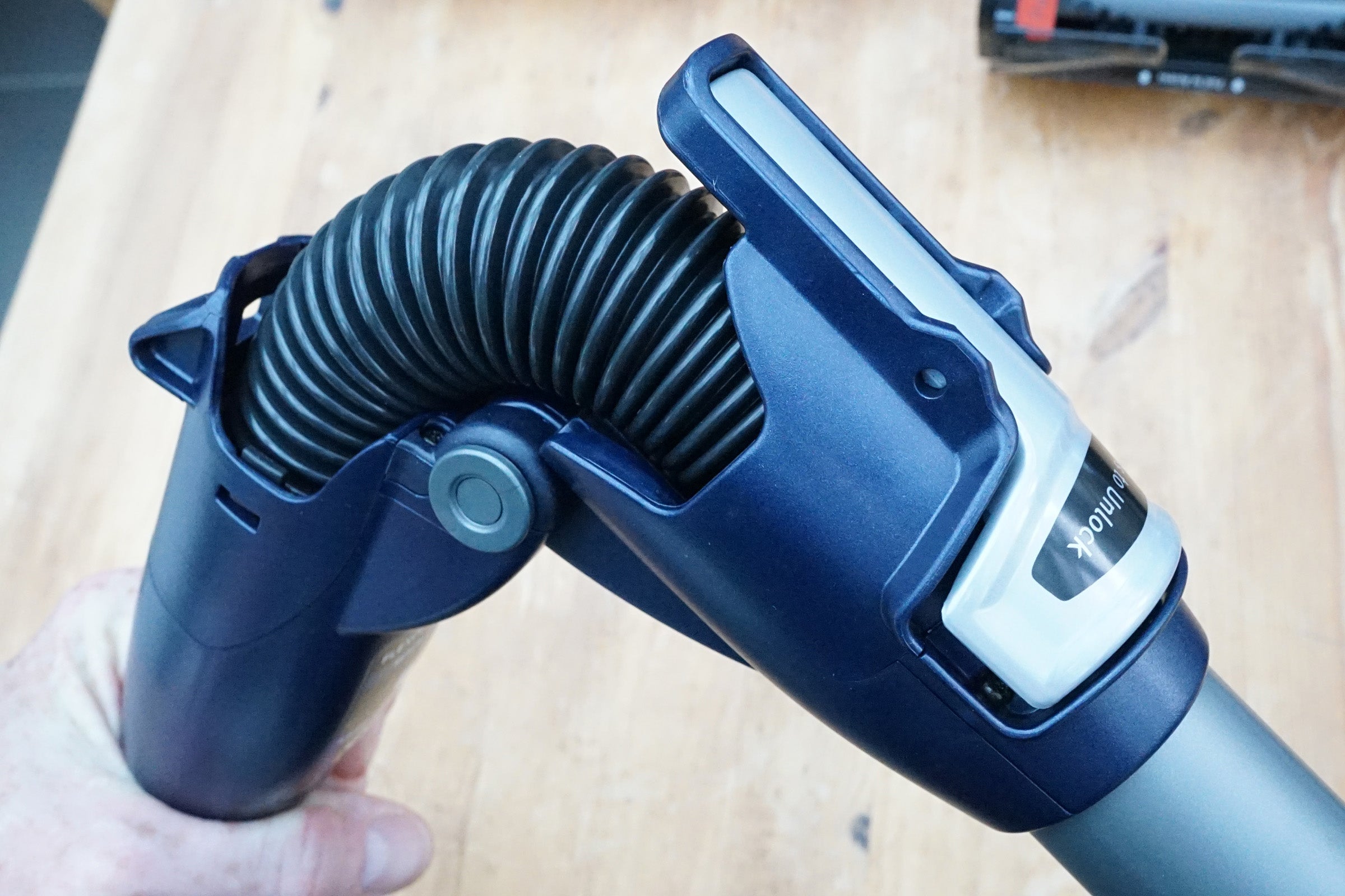 Hand holding Shark DuoClean Cordless vacuum wand and flexible hose.