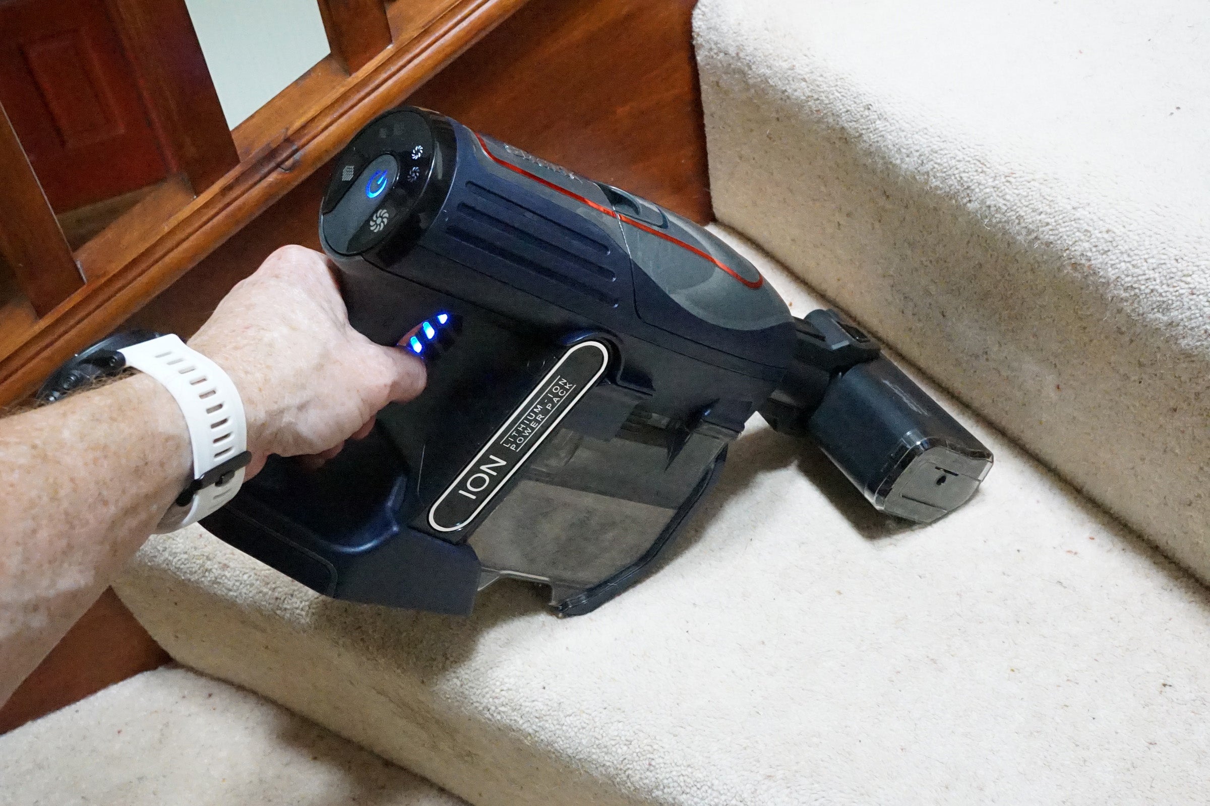 Hand holding Shark DuoClean Cordless Vacuum on carpeted stairs