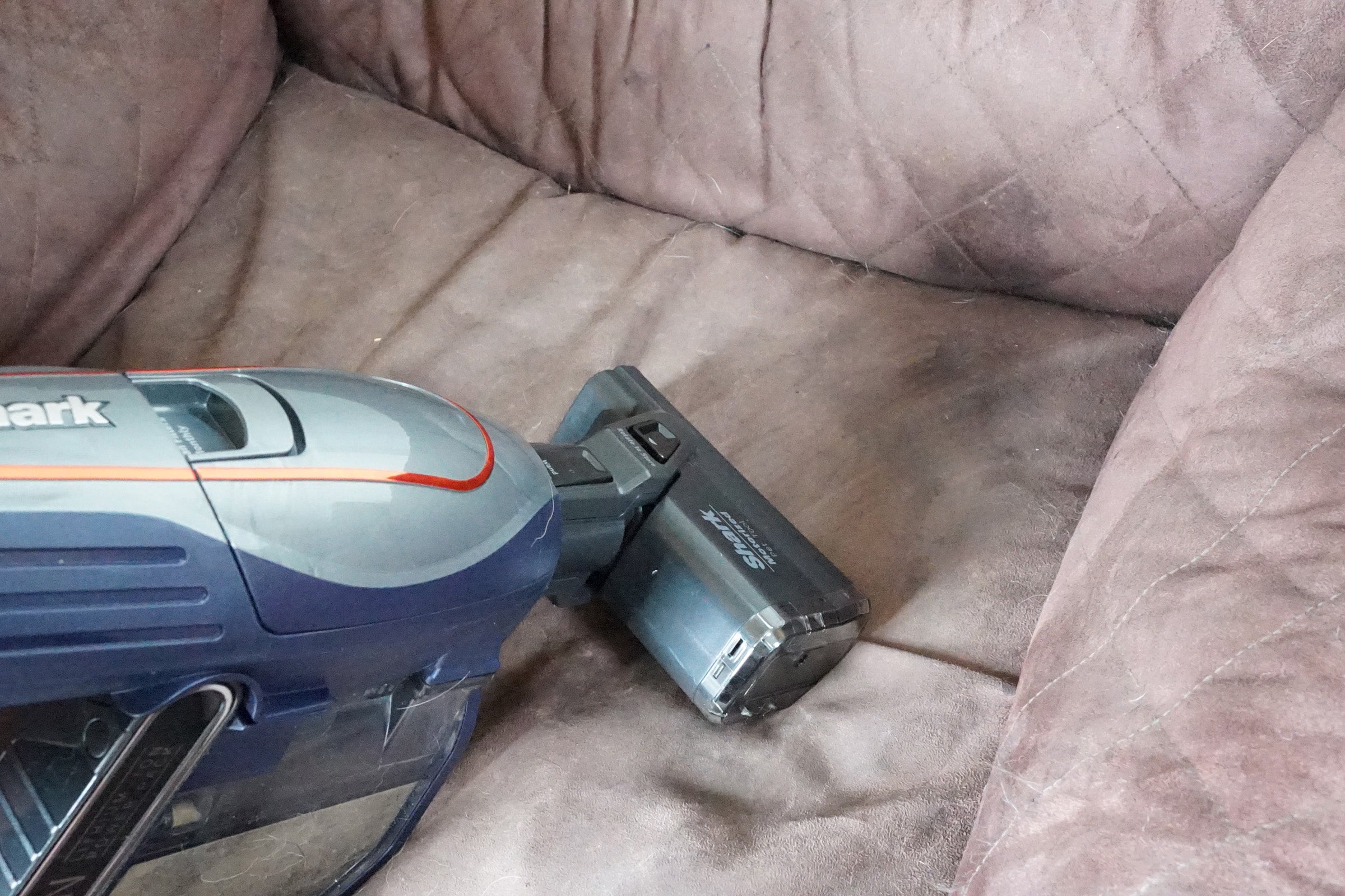 Shark DuoClean Cordless Vacuum on a brown sofa.