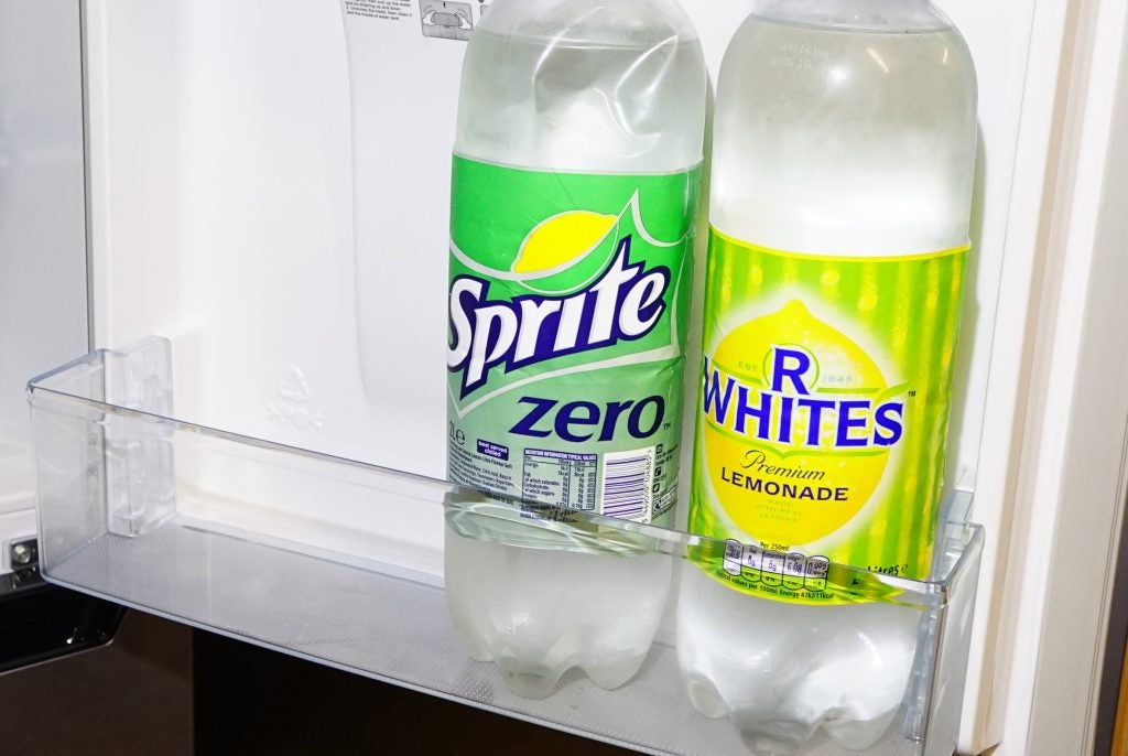 Soft drink bottles on refrigerator shelf.