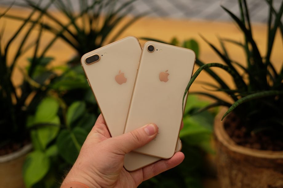 Hand holding iPhone 8 and iPhone 8 Plus for comparison.