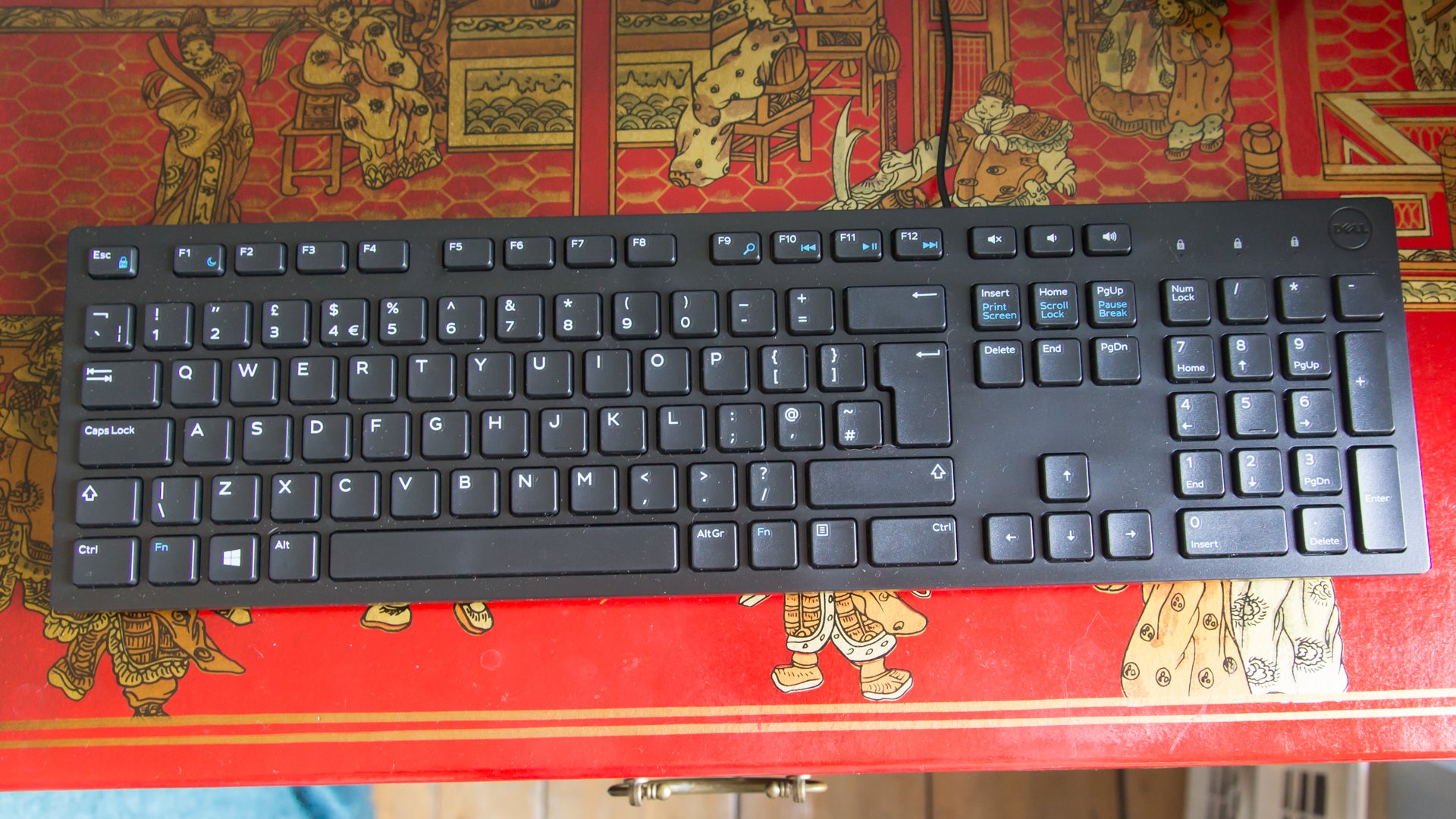 Dell keyboard on a decorative red table.