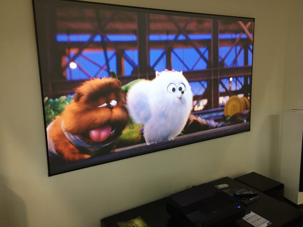 Epson EH-LS100 projector displaying animation on screen.
