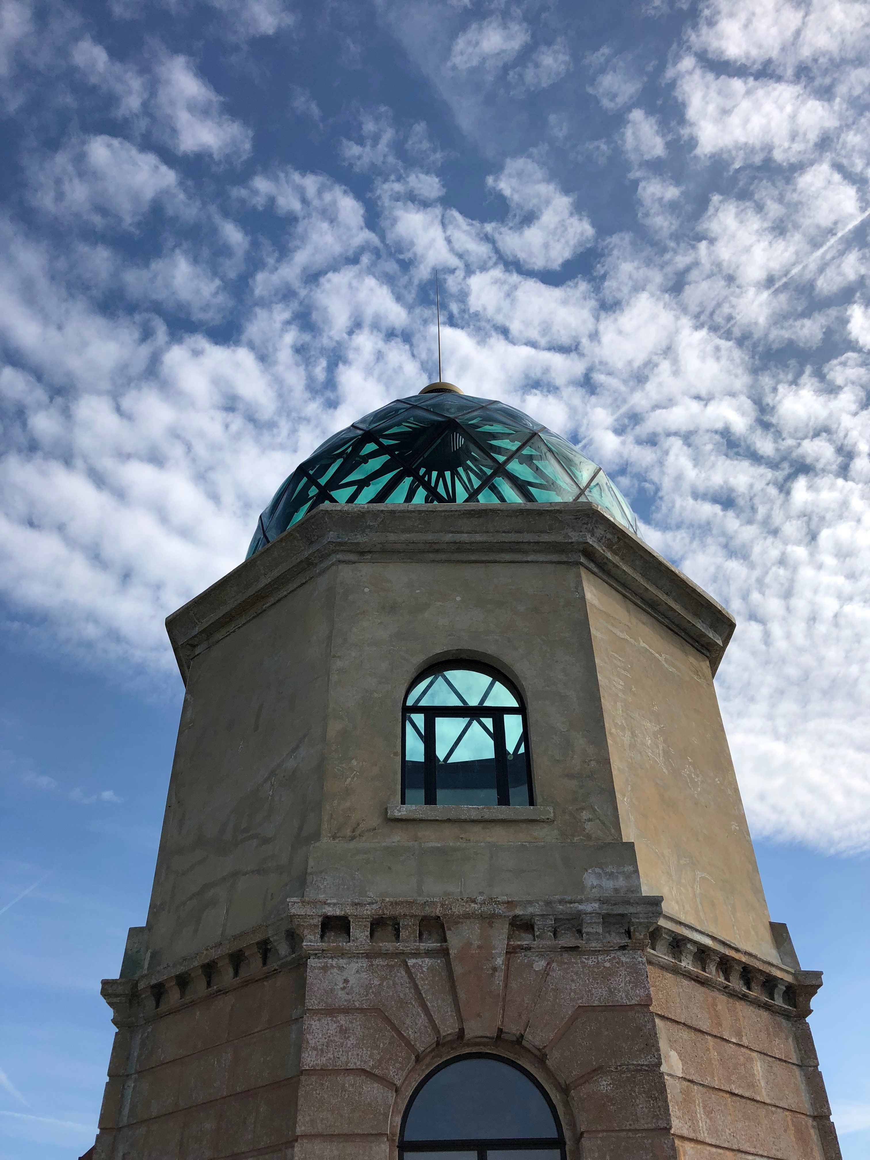 Historic tower with a turquoise dome against a cloudy sky.
