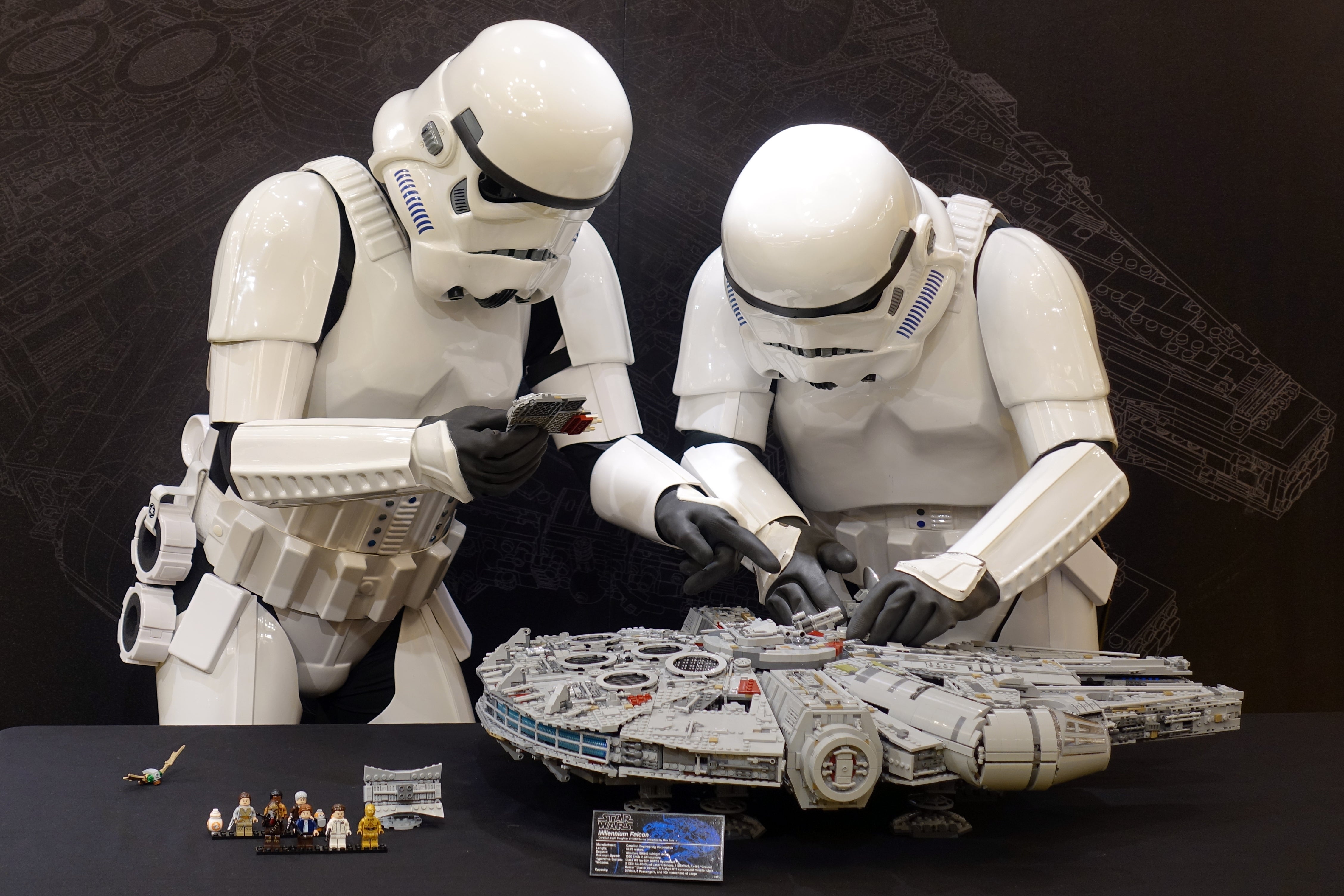 Stormtroopers assembling Lego Millennium Falcon model.