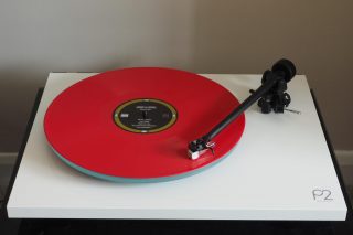 Red vinyl record playing on a Rega Planar 2 turntable.
