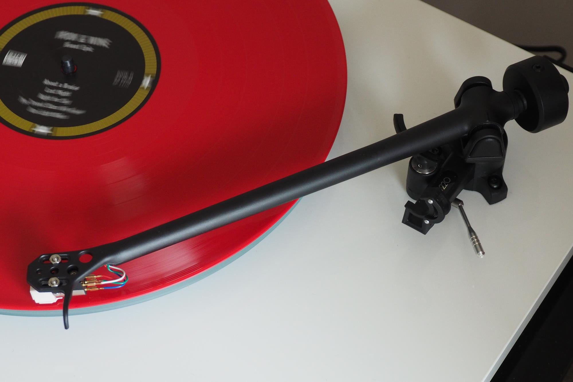 Close-up of Rega Planar 2 turntable with red vinyl record spinning.