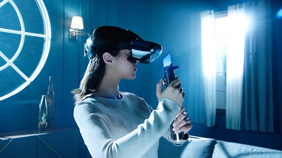 Person playing with Lenovo Mirage AR headset and lightsaber controller.