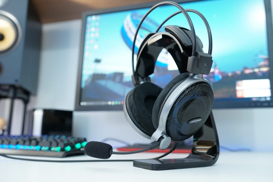 Audio-Technica ATH-ADG1X gaming headset on stand with computer background.