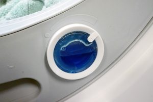 Close-up of Miele washing machine detergent dispenser with blue liquid.