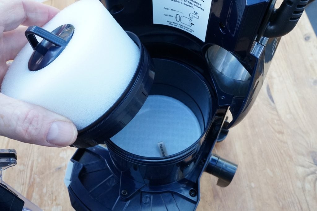 Hand removing foam filter from Shark vacuum cleaner