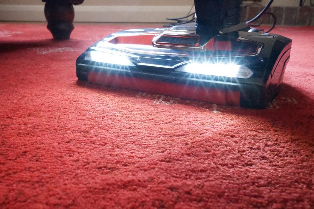 Shark DuoClean vacuum cleaner in use on red carpet.
