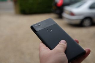 Hand holding Google Pixel 2 smartphone with blurred background.