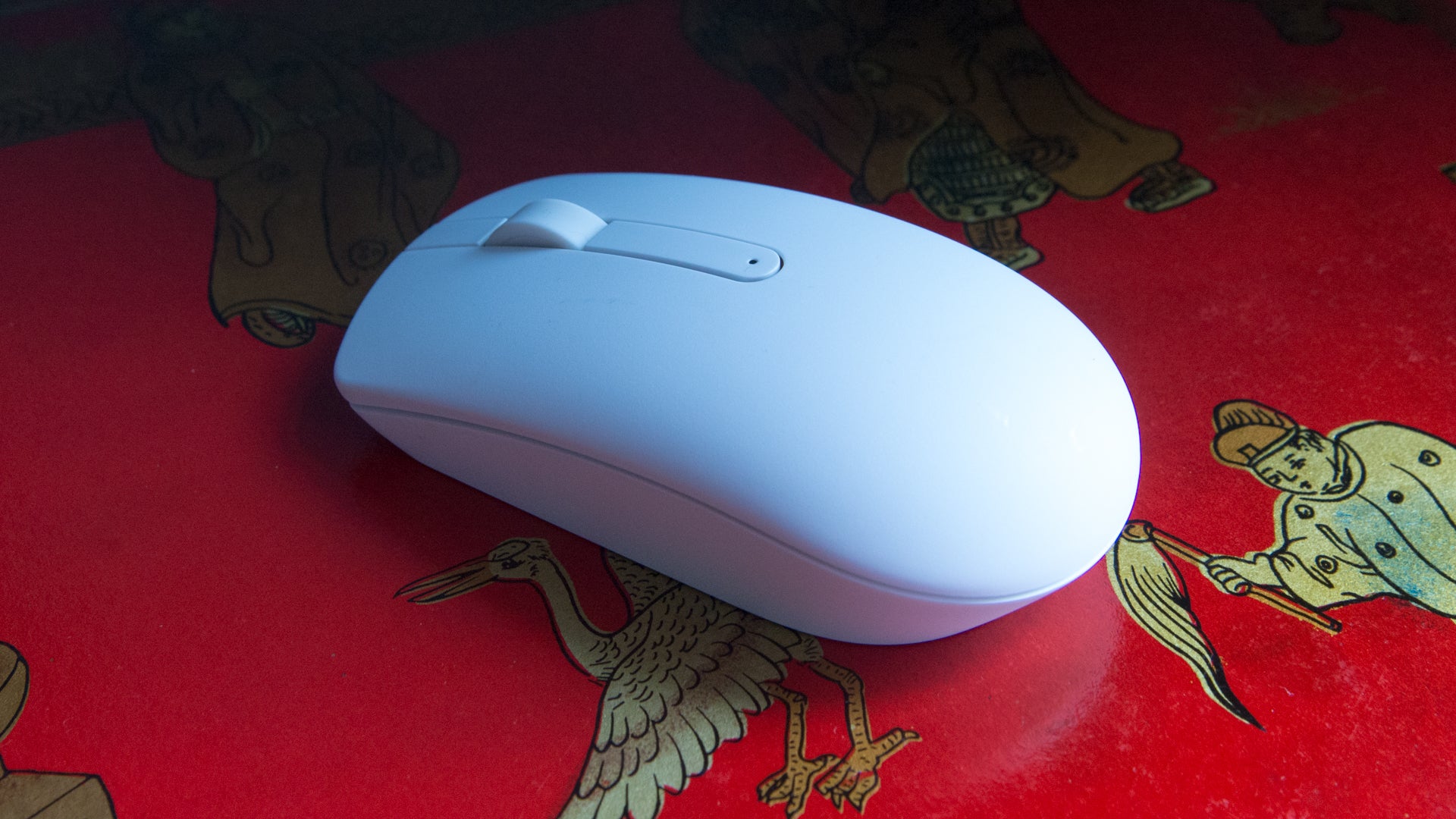 White computer mouse on patterned red surface.