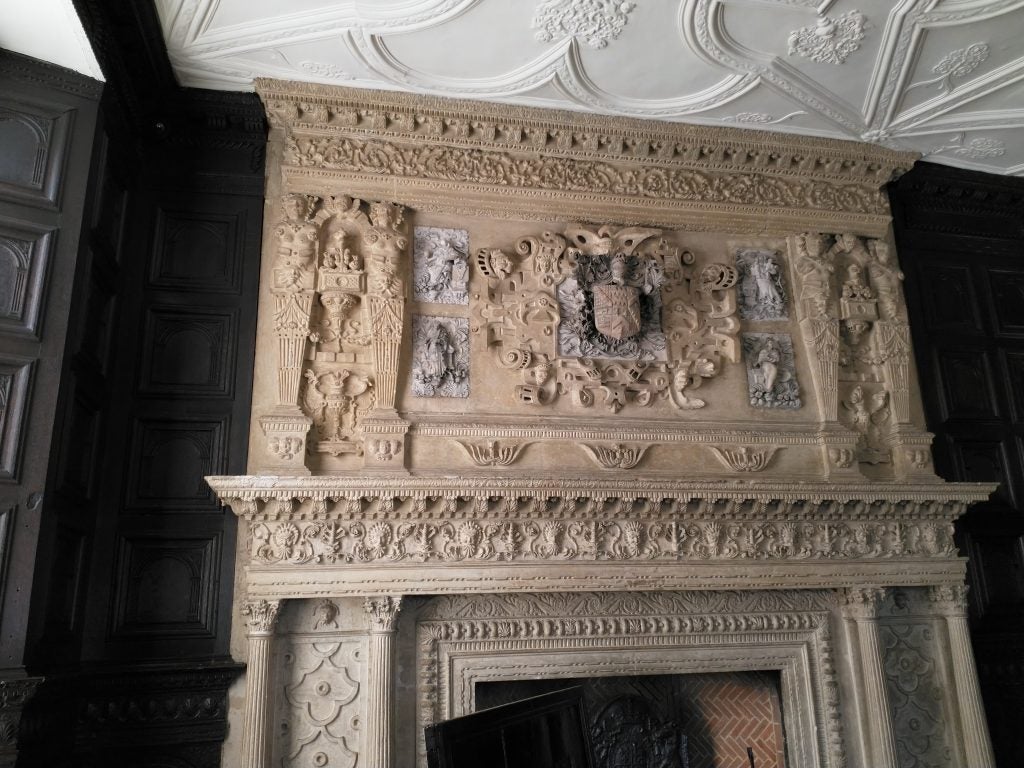 Ornate stone fireplace with intricate carvings in a historic room.
