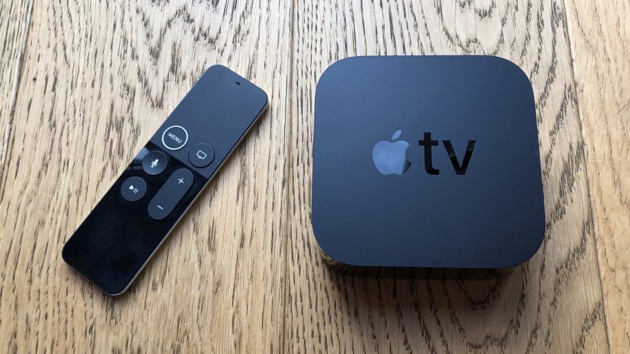 Apple TV 4K and remote on wooden surface.