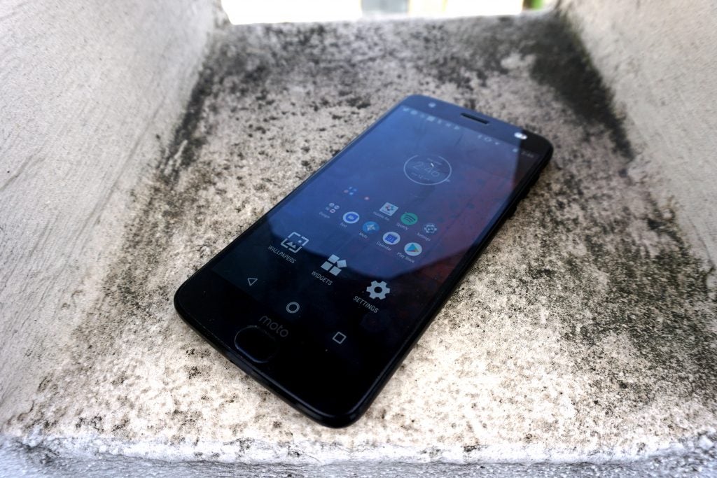 Moto Z2 Force smartphone on concrete surface.