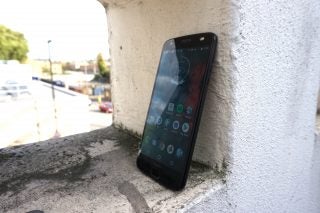 Moto Z2 Force smartphone leaning against a wall outdoors.