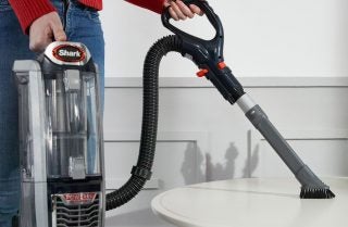 Person using Shark DuoClean vacuum on a table.