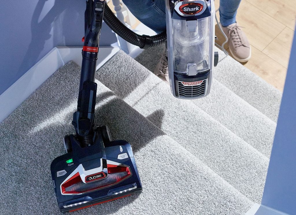 Shark DuoClean vacuum in use on carpeted stairs.