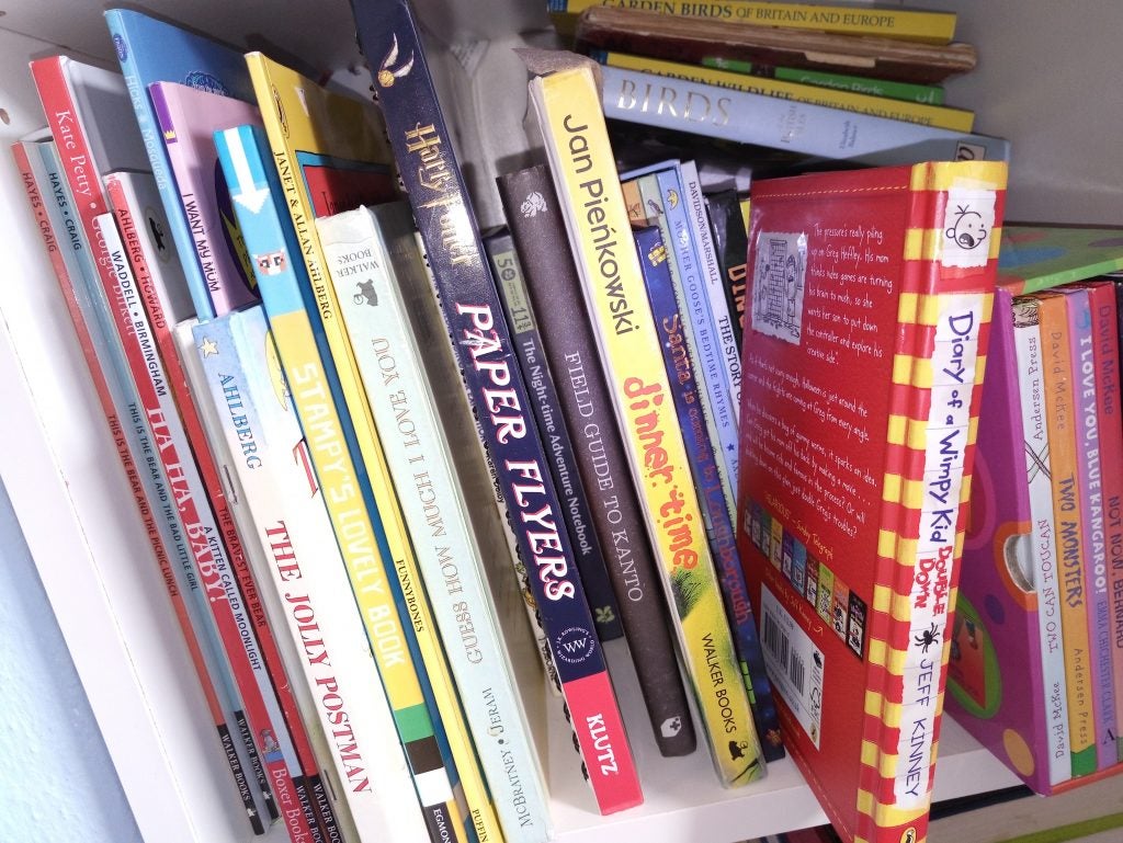 Assorted children's books on a white shelf.