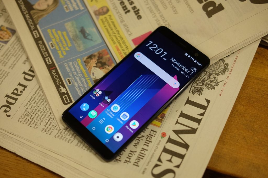 HTC U11+ smartphone on top of a newspaper.