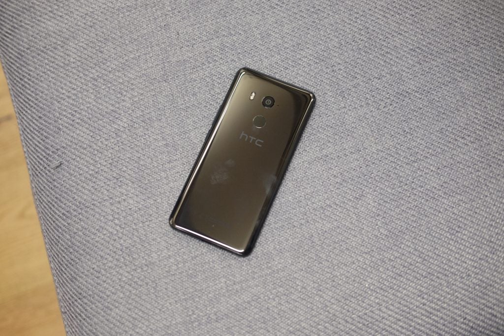 HTC U11+ smartphone on textured grey fabric surface.