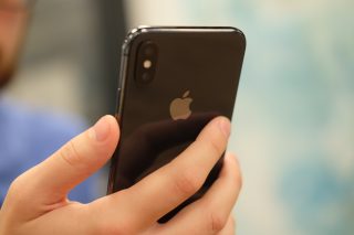 Person holding an iPhone X showing the rear camera.
