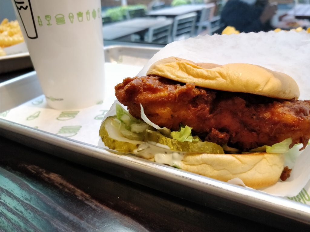 Close-up of a chicken sandwich with lettuce on a tray.