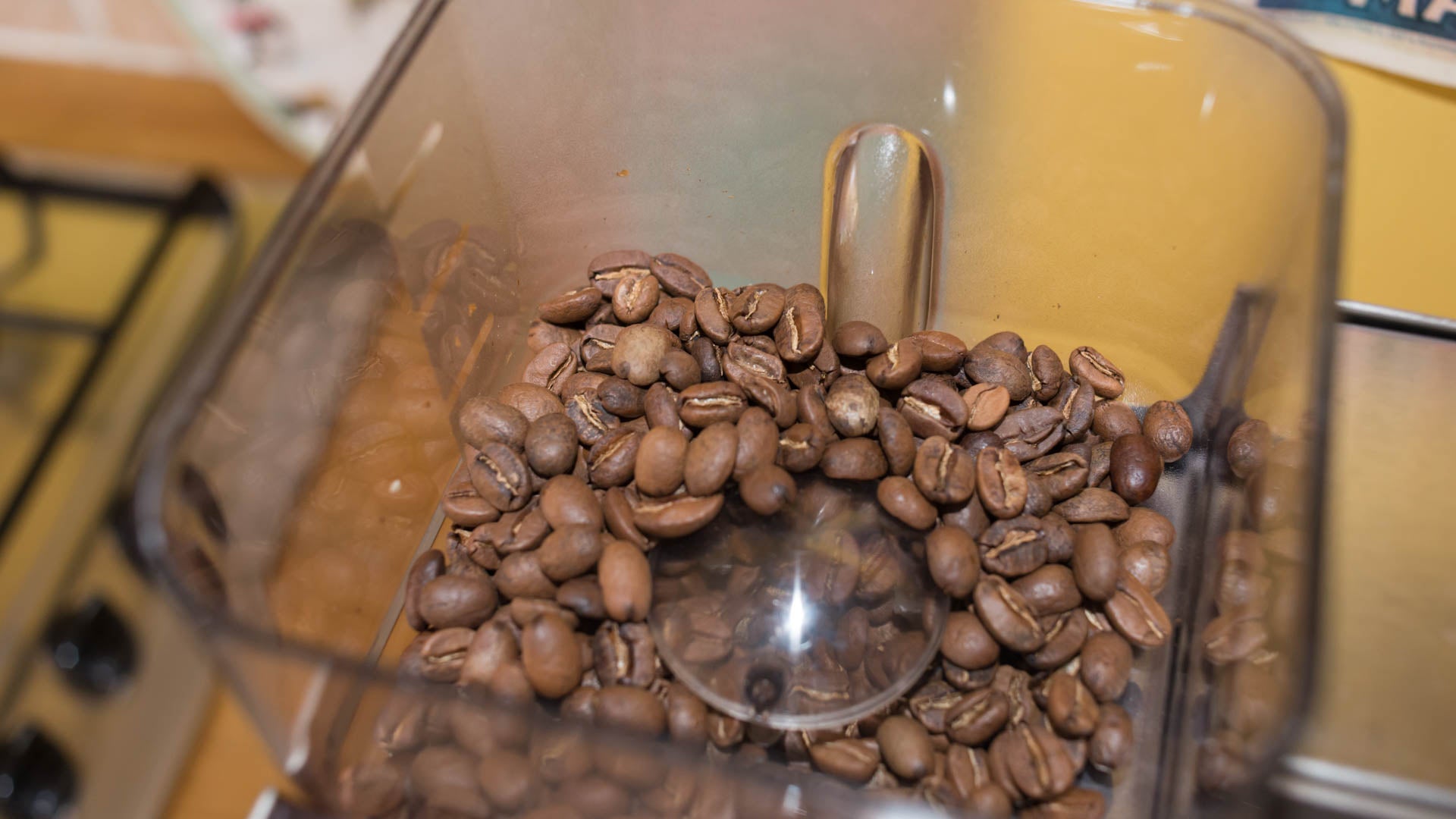 Close-up of coffee beans in espresso machine grinder hopper