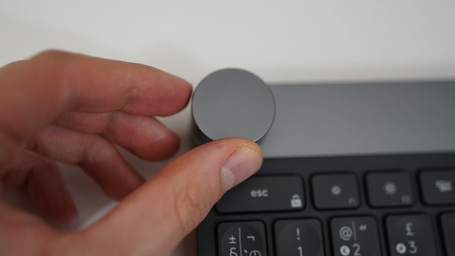 Hand adjusting the dial on a Logitech Craft keyboard.