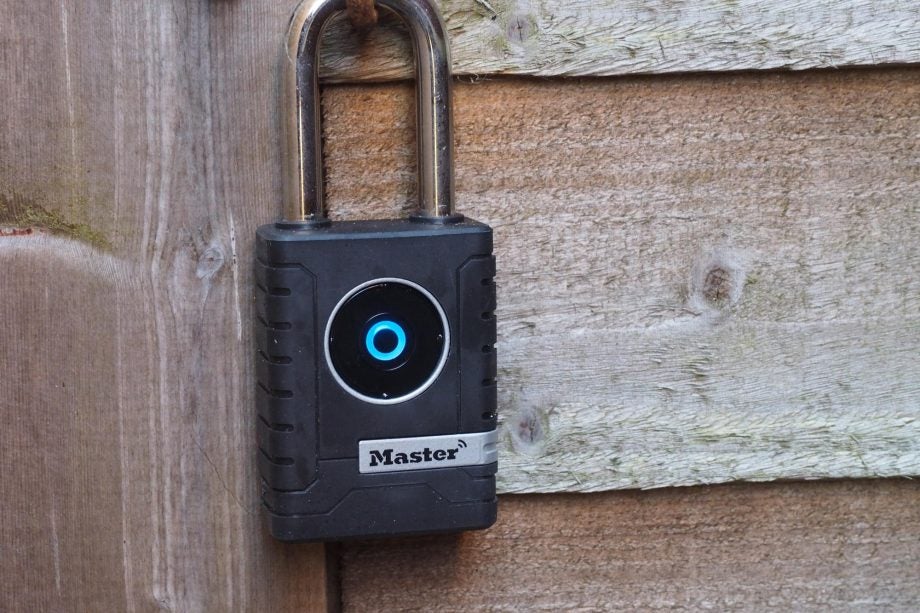 Master Lock Smart Outdoor Padlock secured to a wooden gate.