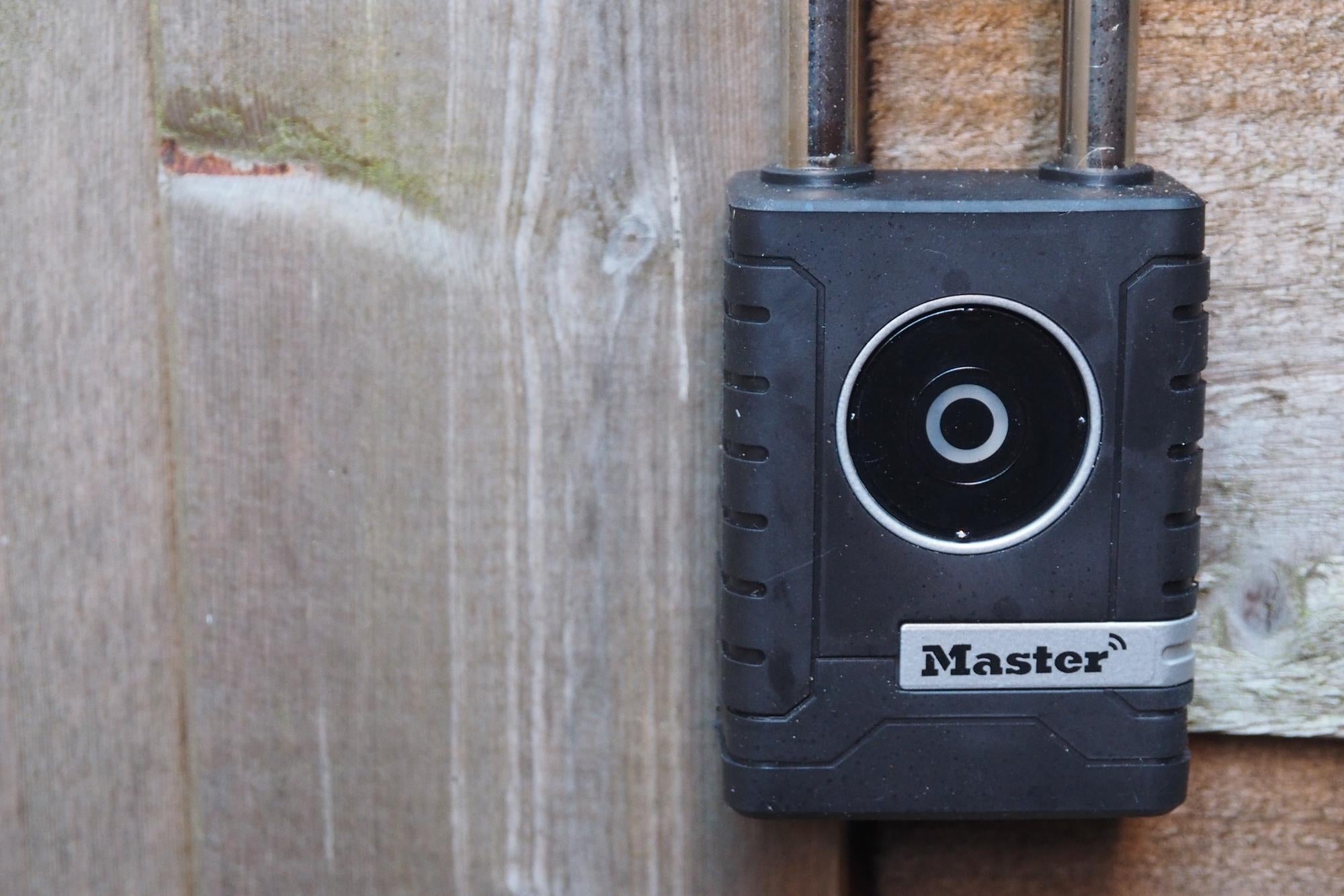 Master Lock Smart Outdoor Padlock on wooden background.
