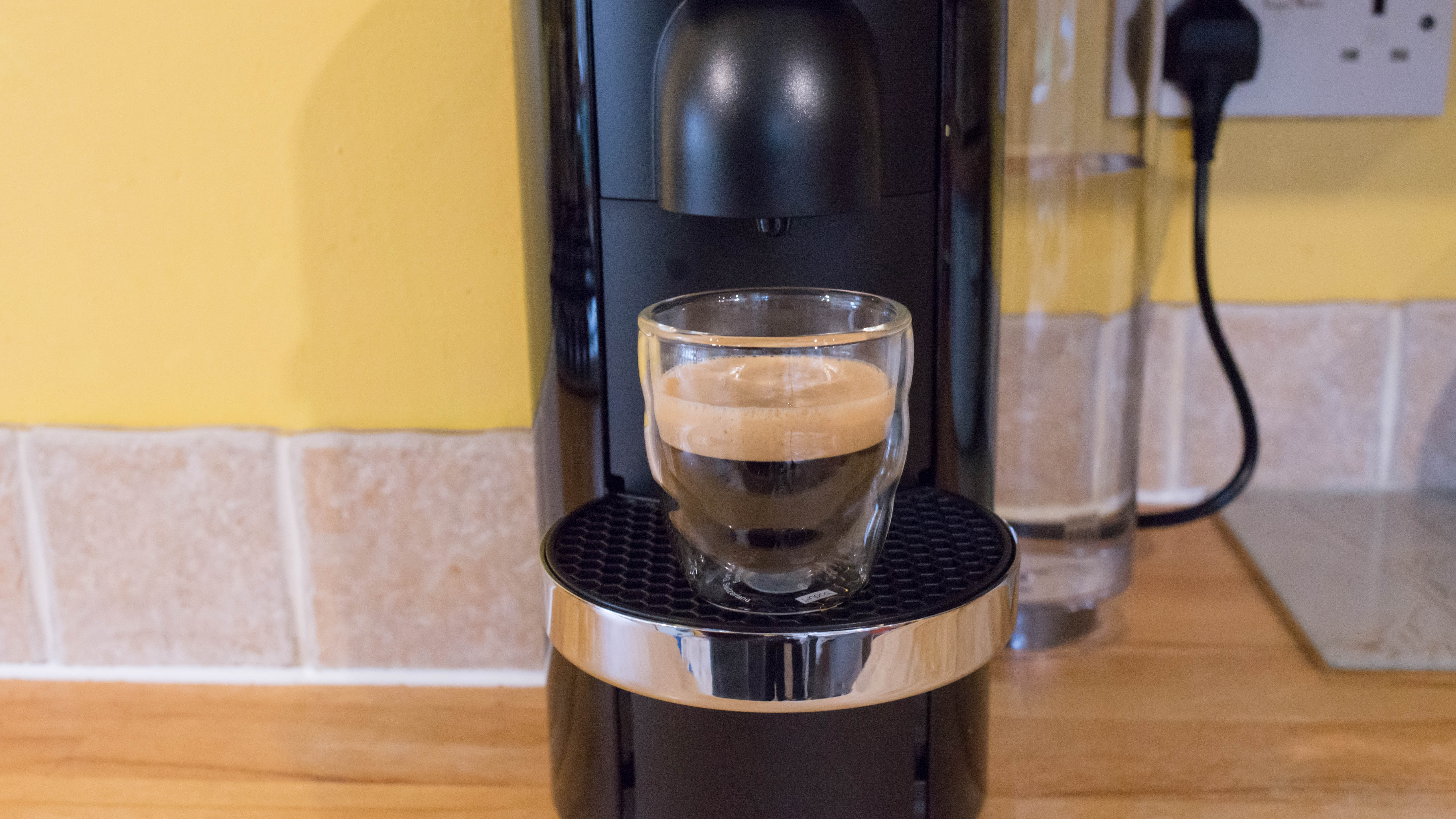 Nespresso Vertuo Plus machine with freshly brewed coffee.