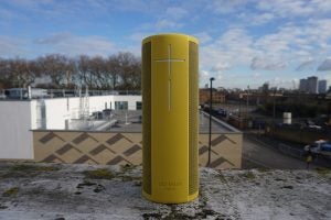 Yellow UE Megablast speaker on a rooftop with city background