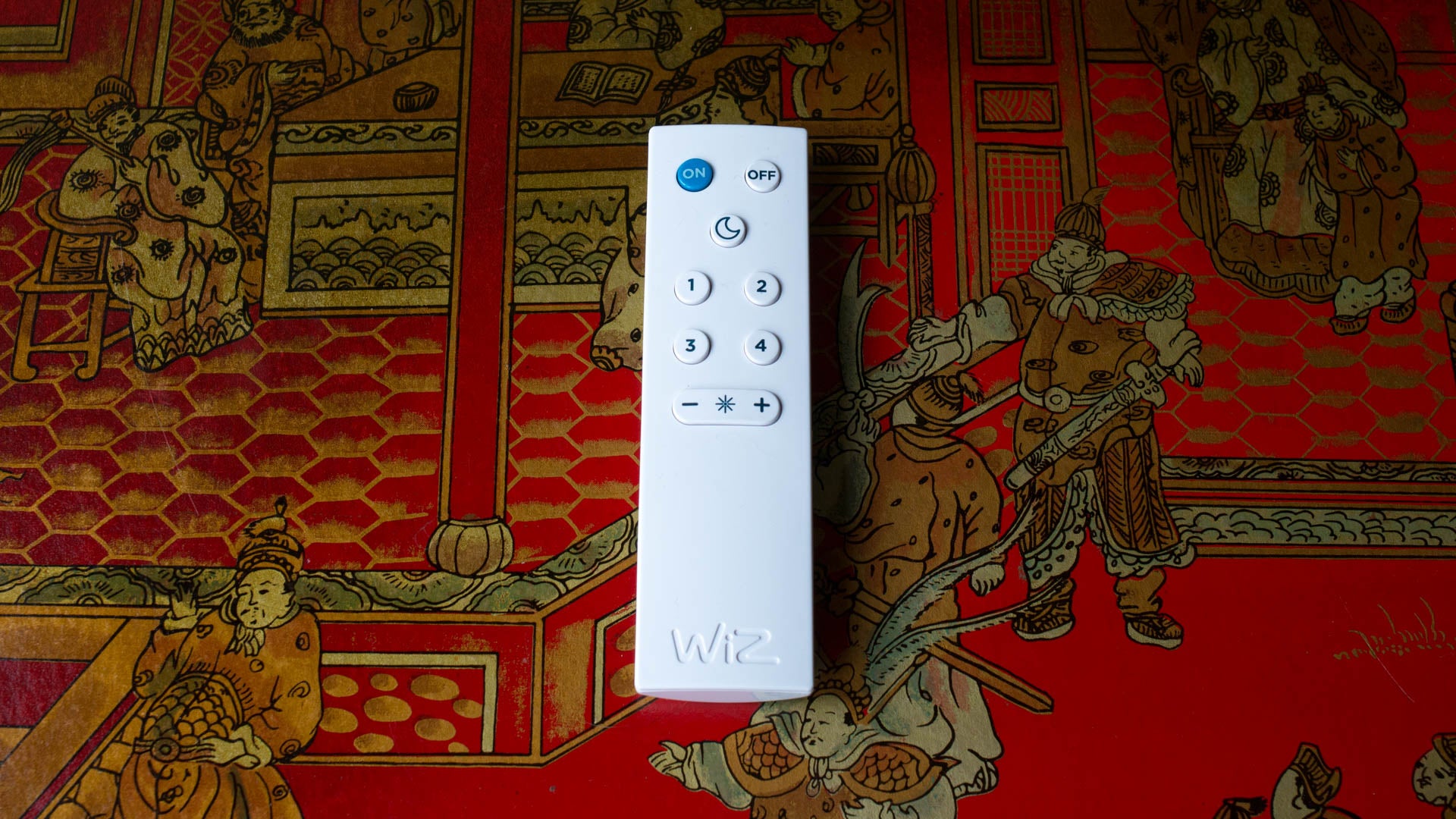 WiZ connected light remote on a colorful illustration background.