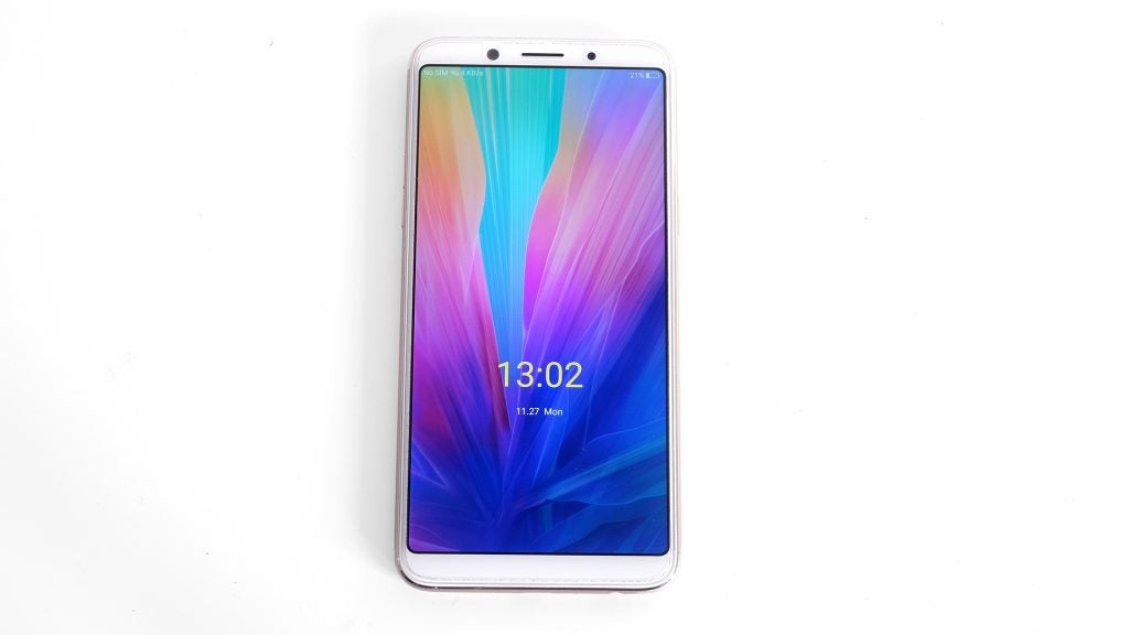 Oppo F5 smartphone lying on a white surface.Oppo F5 smartphone displaying colorful screen on white background.