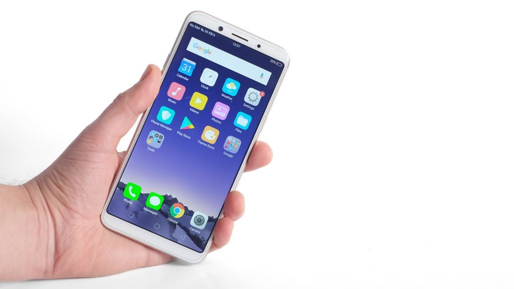 Hand holding Oppo F5 smartphone displaying home screen.