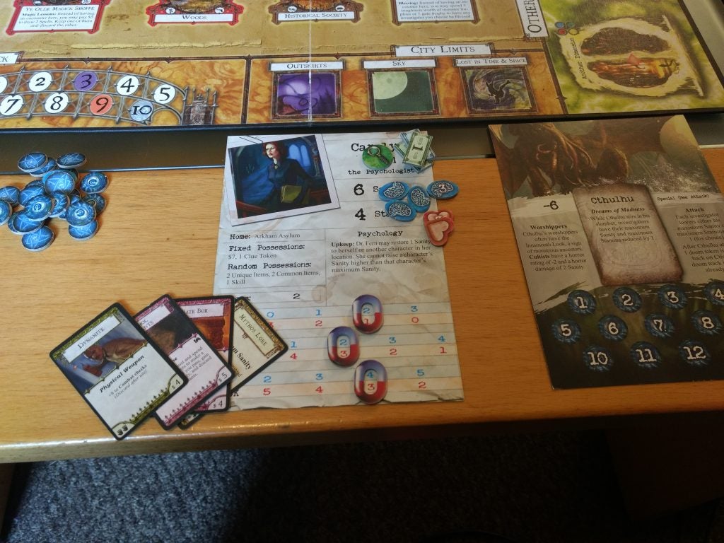 Arkham Horror board game setup with character sheets and cards.