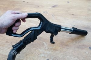 Hand holding Hotpoint vacuum cleaner handle and hose