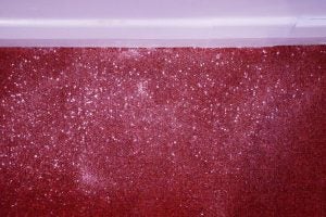 Red carpet with white particles and skirting board.