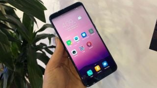 Honor View 10 smartphone held in hand with screen on.