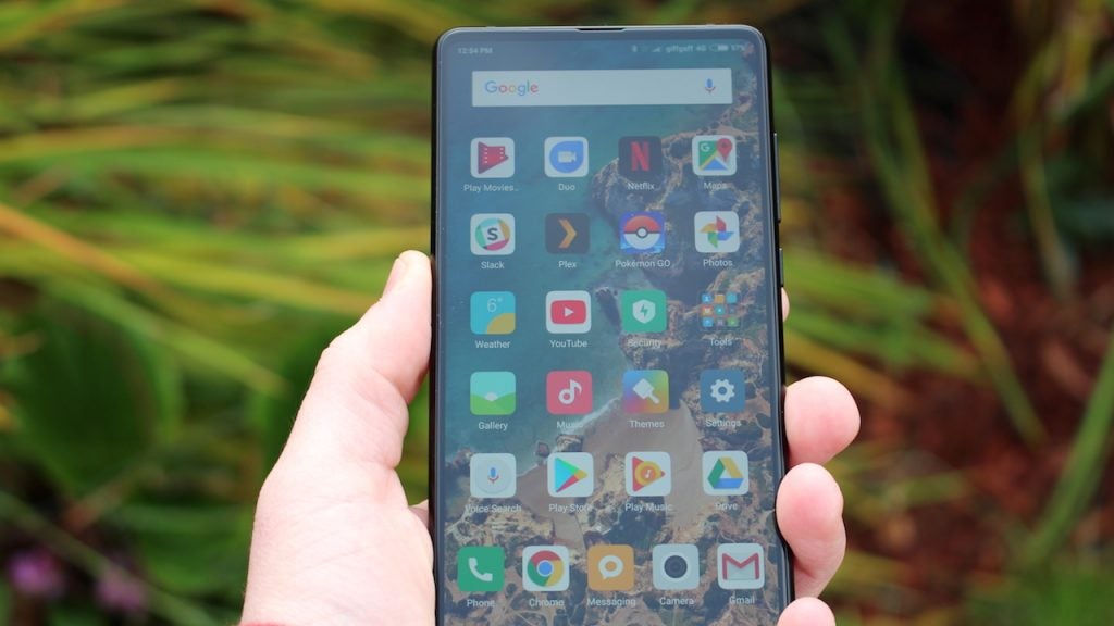 Hand holding Xiaomi Mi Mix 2 displaying apps on screen.