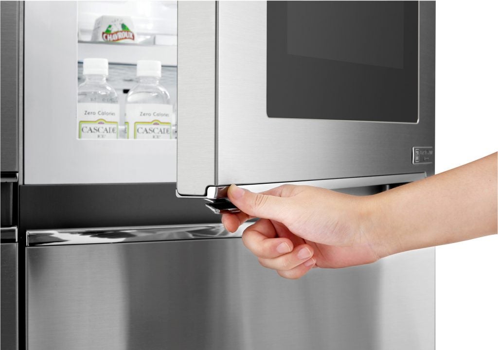 Hand opening LG stainless steel fridge freezer door.