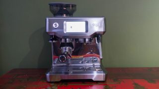 Sage Barista Touch espresso machine on a red table.