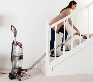Person using Vax carpet cleaner on staircase.