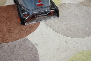 Bissell StainPro 10Bissell StainPro 10 carpet cleaner in use on multicolored rug.