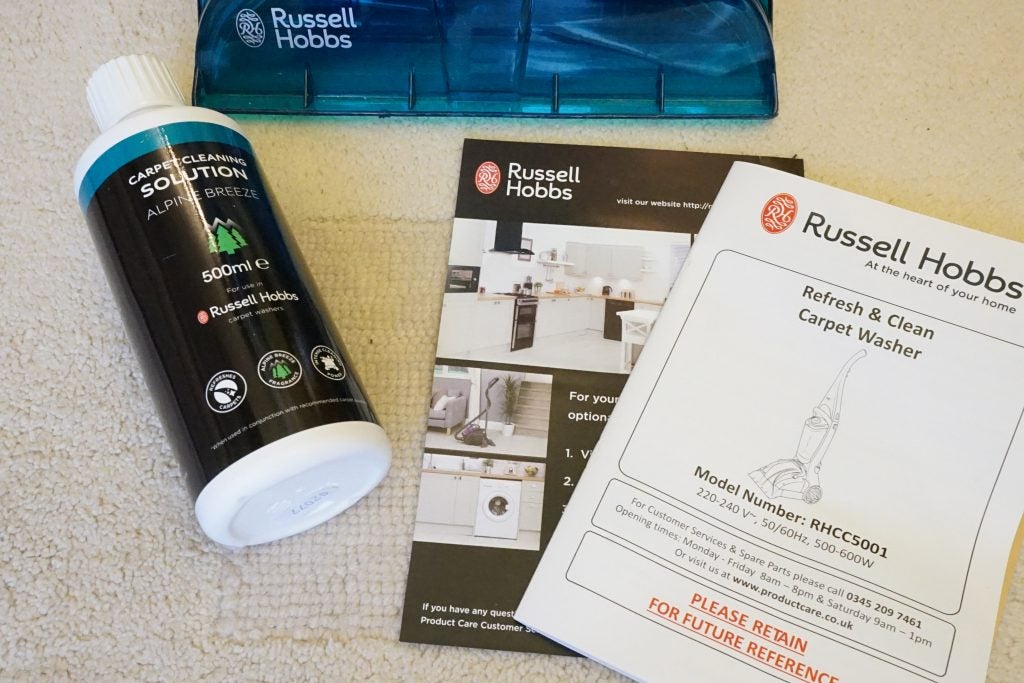 Russell Hobbs carpet cleaner, cleaning solution bottle, and manuals.