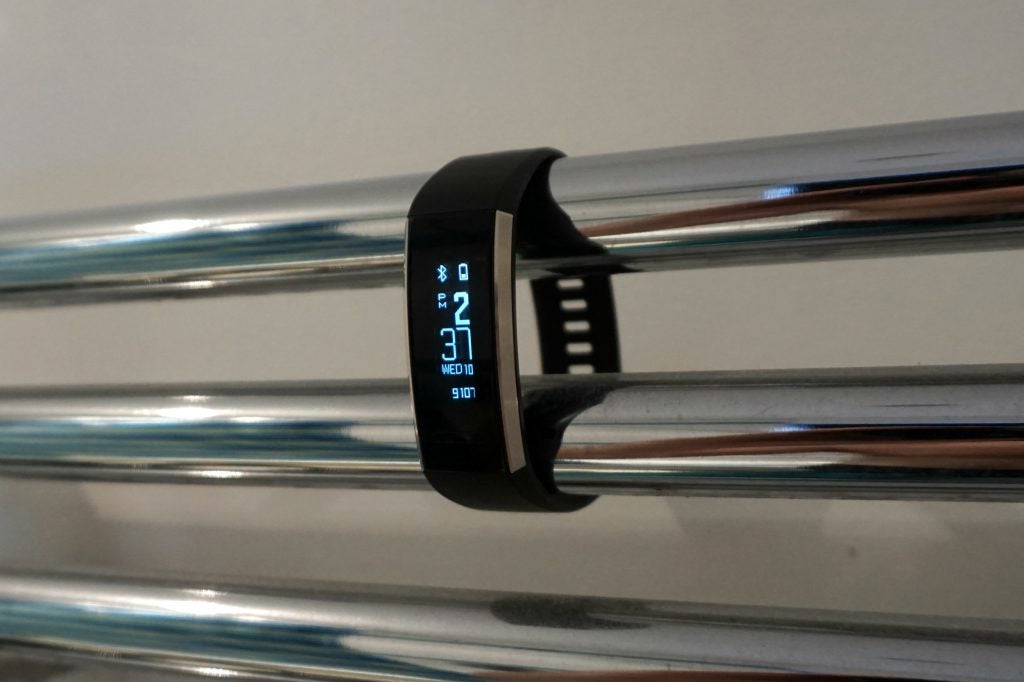 Huawei Band 2 Pro on a metallic surface displaying time and date.