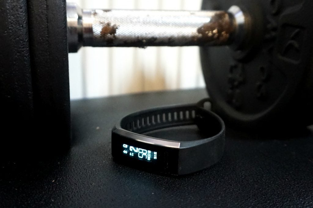 Huawei Band 2 Pro fitness tracker on a table with weights in background.